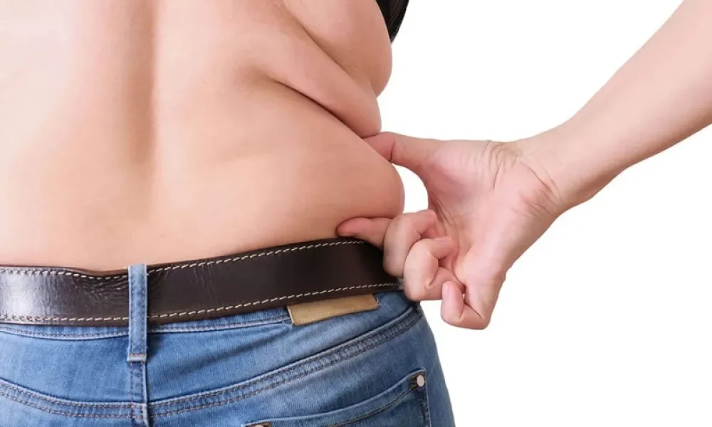 Woman pinching love handles, illustrating waistline reduction and fat loss solutions in Denville, NJ.